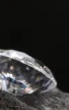 Two polished diamonds sitting on a black rock