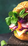 A burger with lettuce, tomatoes, and onions