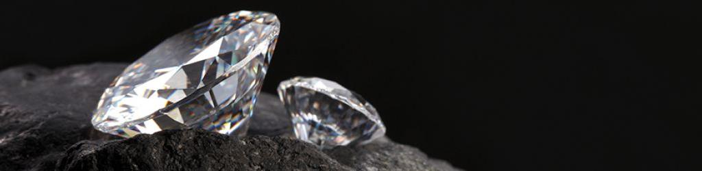 Two polished diamonds sitting on a black rock