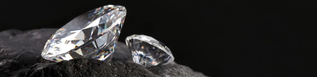 Two polished diamonds sitting on a black rock