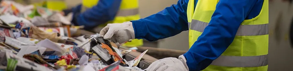 People in yellow safety vests wearing gloves while picking through trash