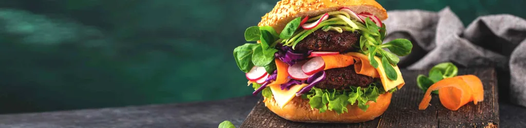 A burger with lettuce, tomatoes, and onions